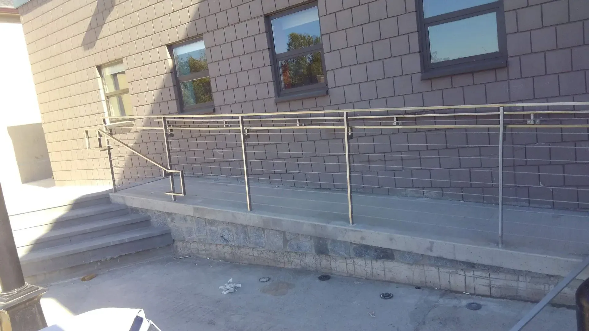 A brick building with stairs and a stainless steel railing.
