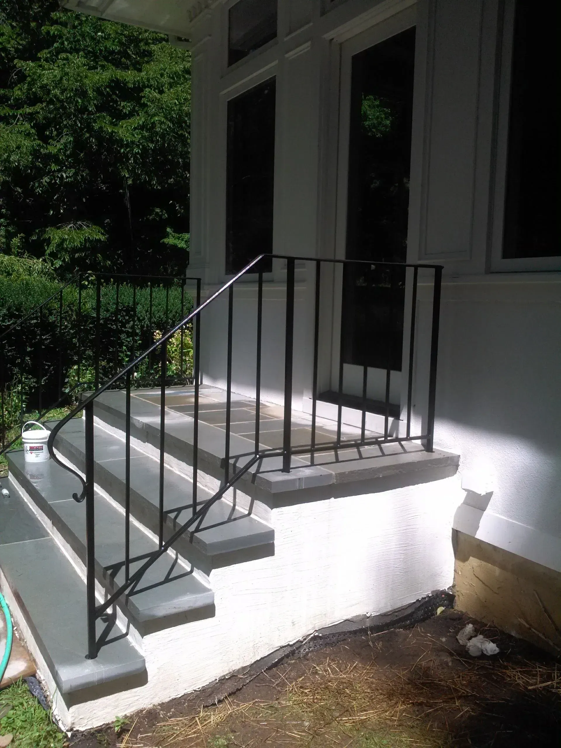 A white house with a black railing and stairs.