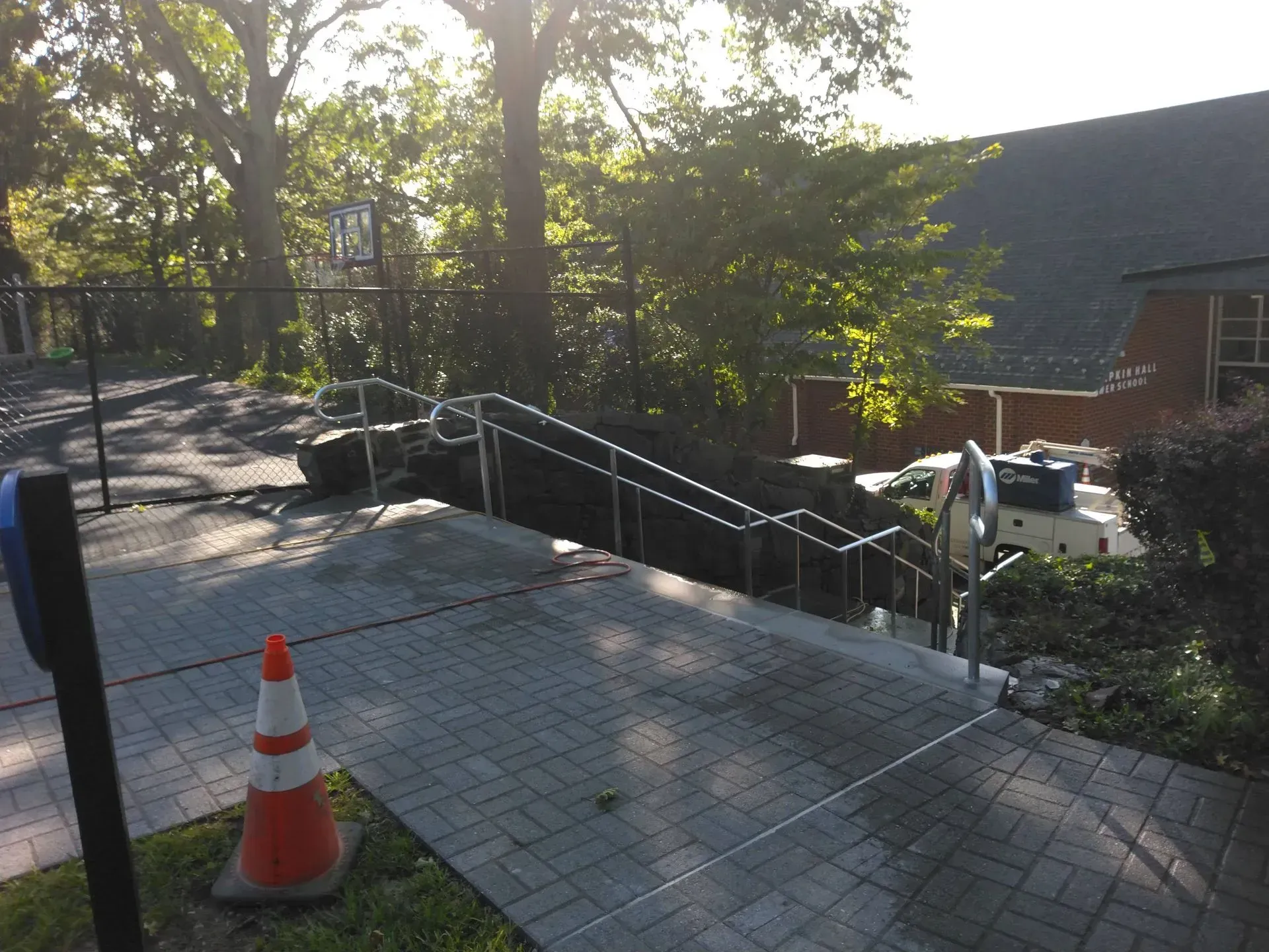 A white and orange traffic cone sits next to a staircase.