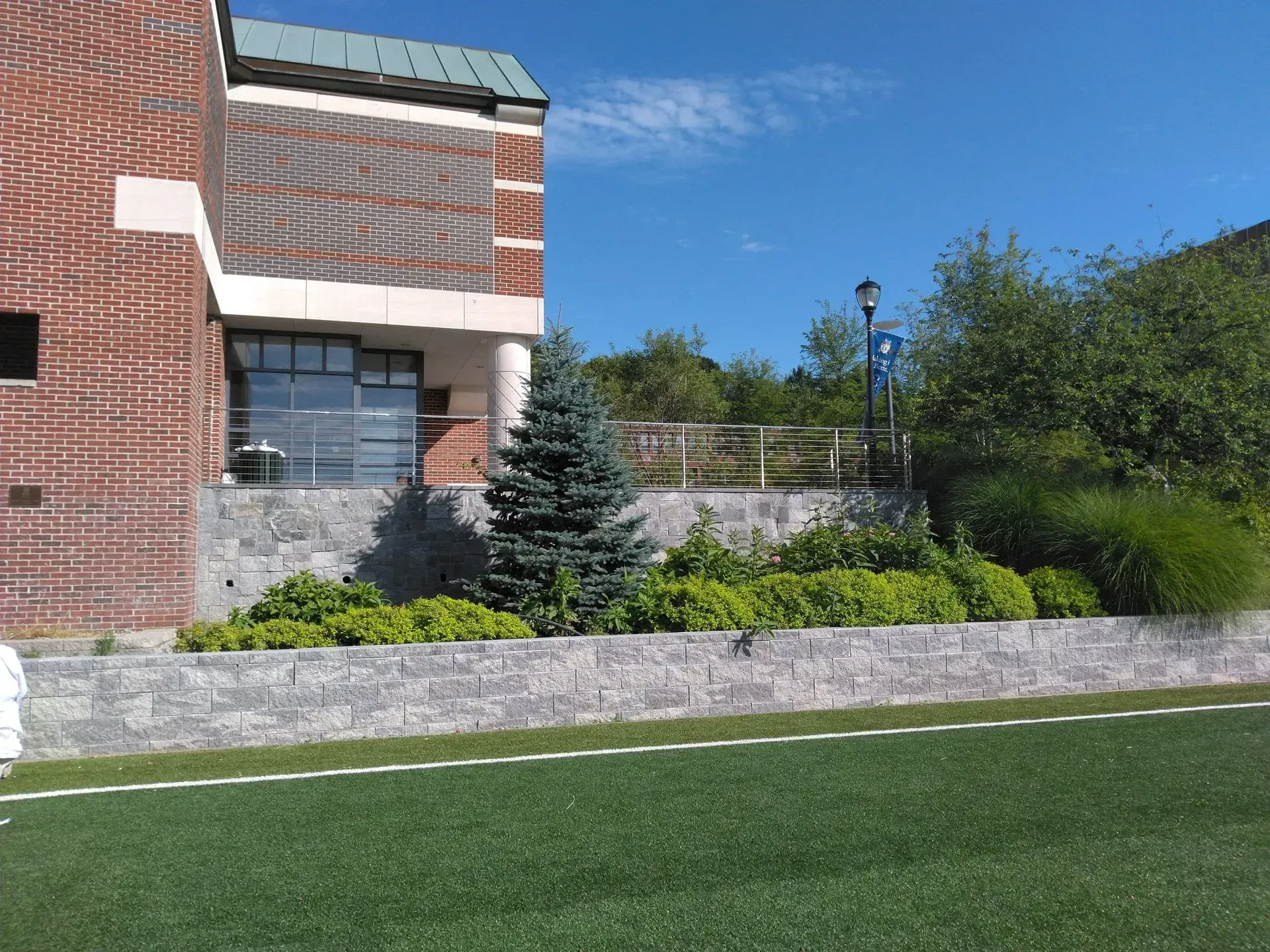 A brick building with a green roof sits next to a grassy field.