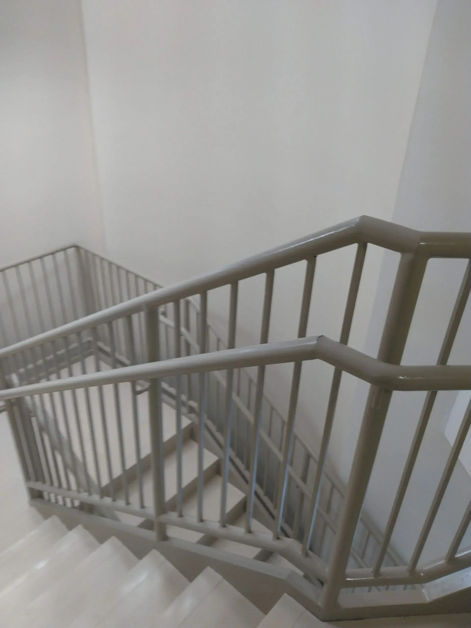 A staircase with a metal railing and a white wall.