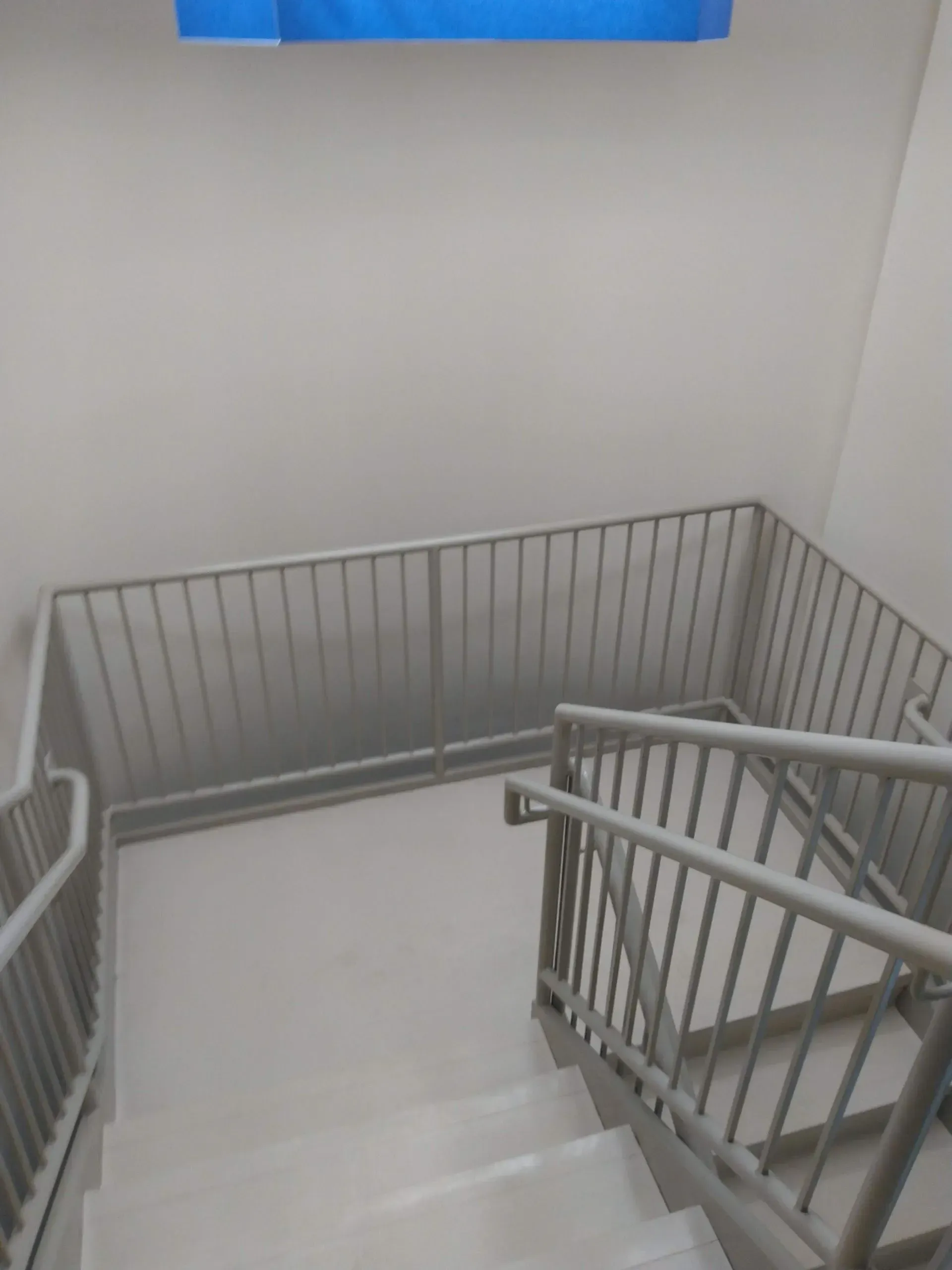 A staircase with a metal railing and a blue tarp hanging from the ceiling.