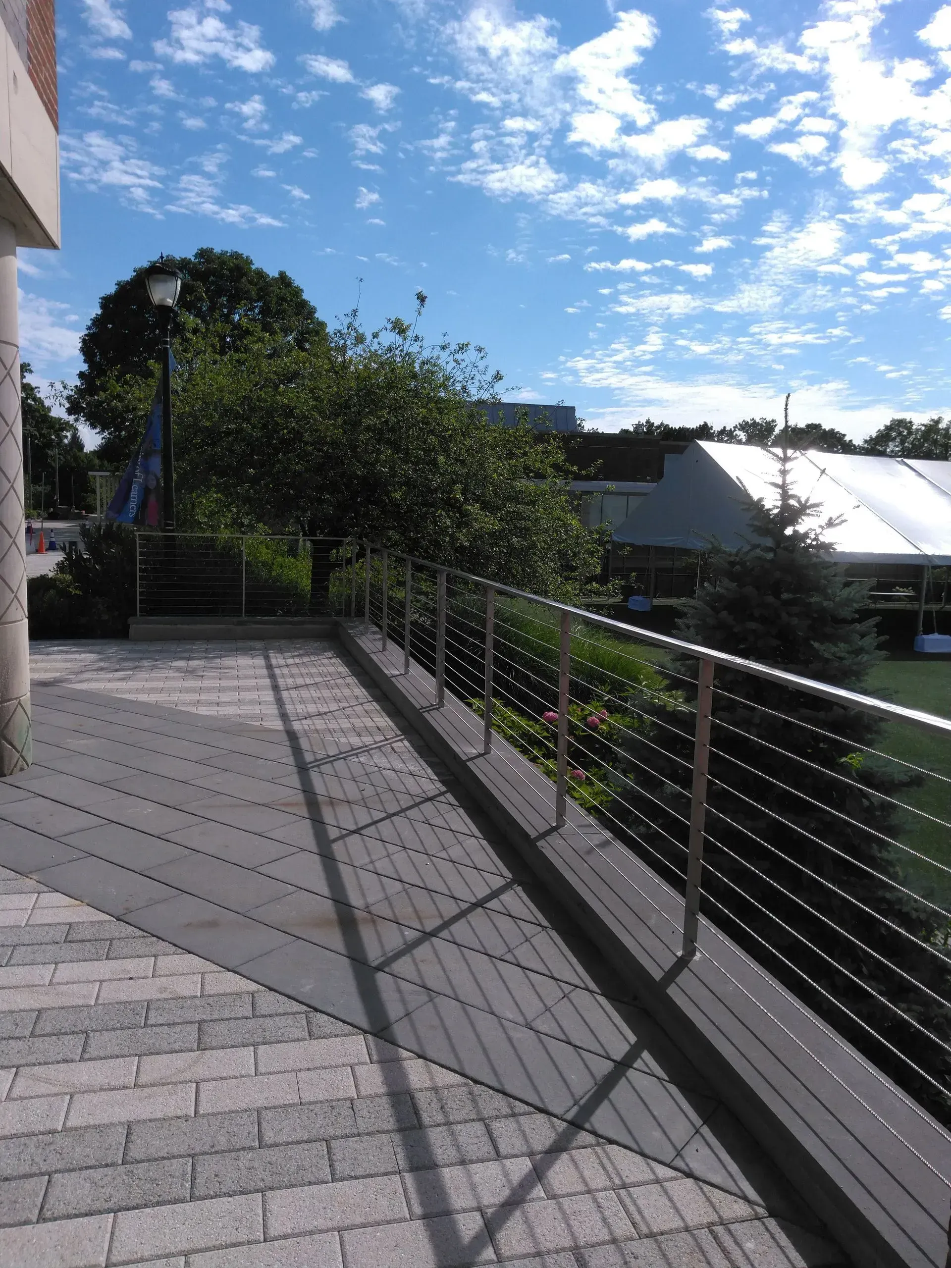 A brick walkway with a stainless steel railing.