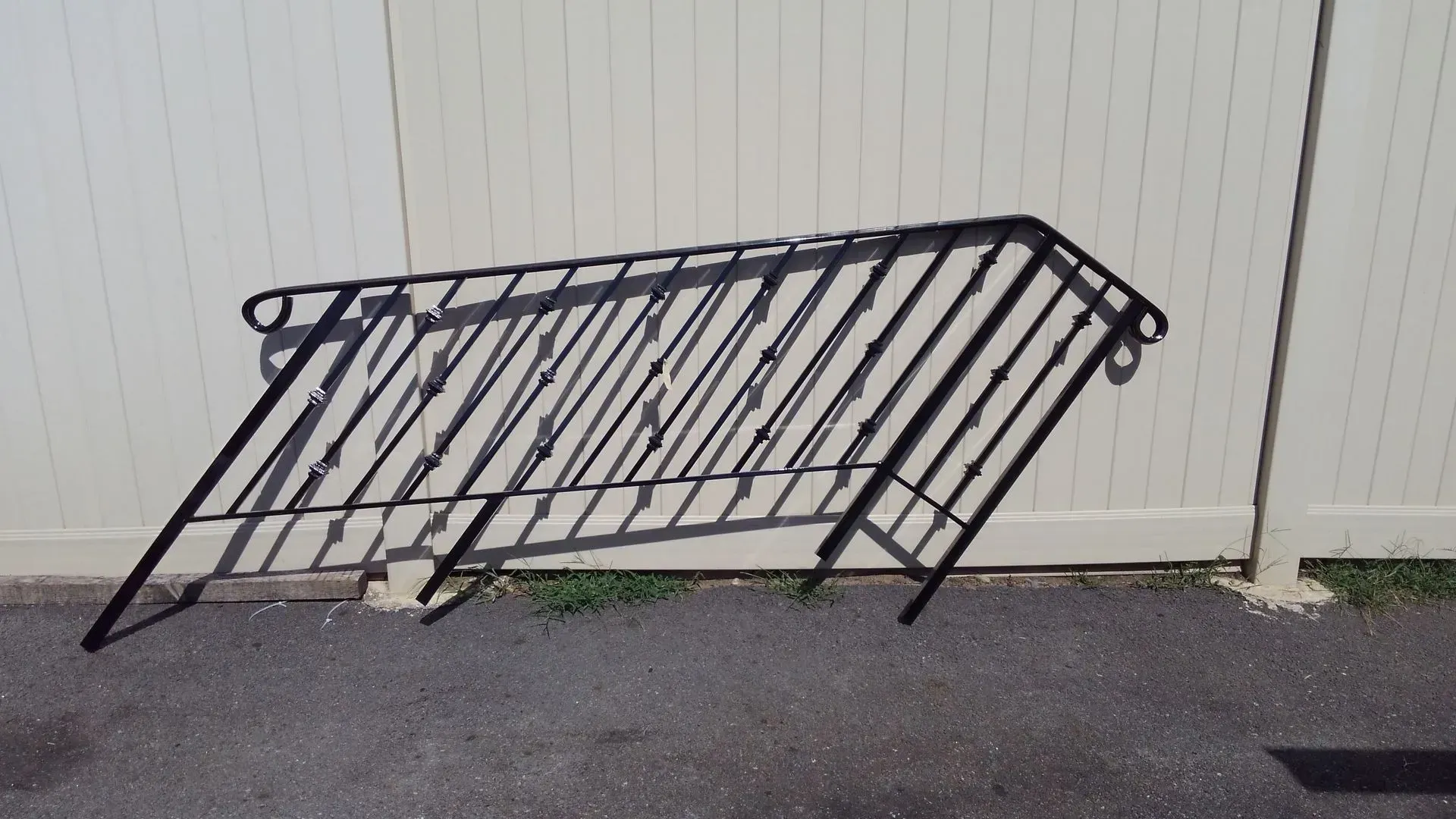 A wrought iron railing is leaning against a white fence.