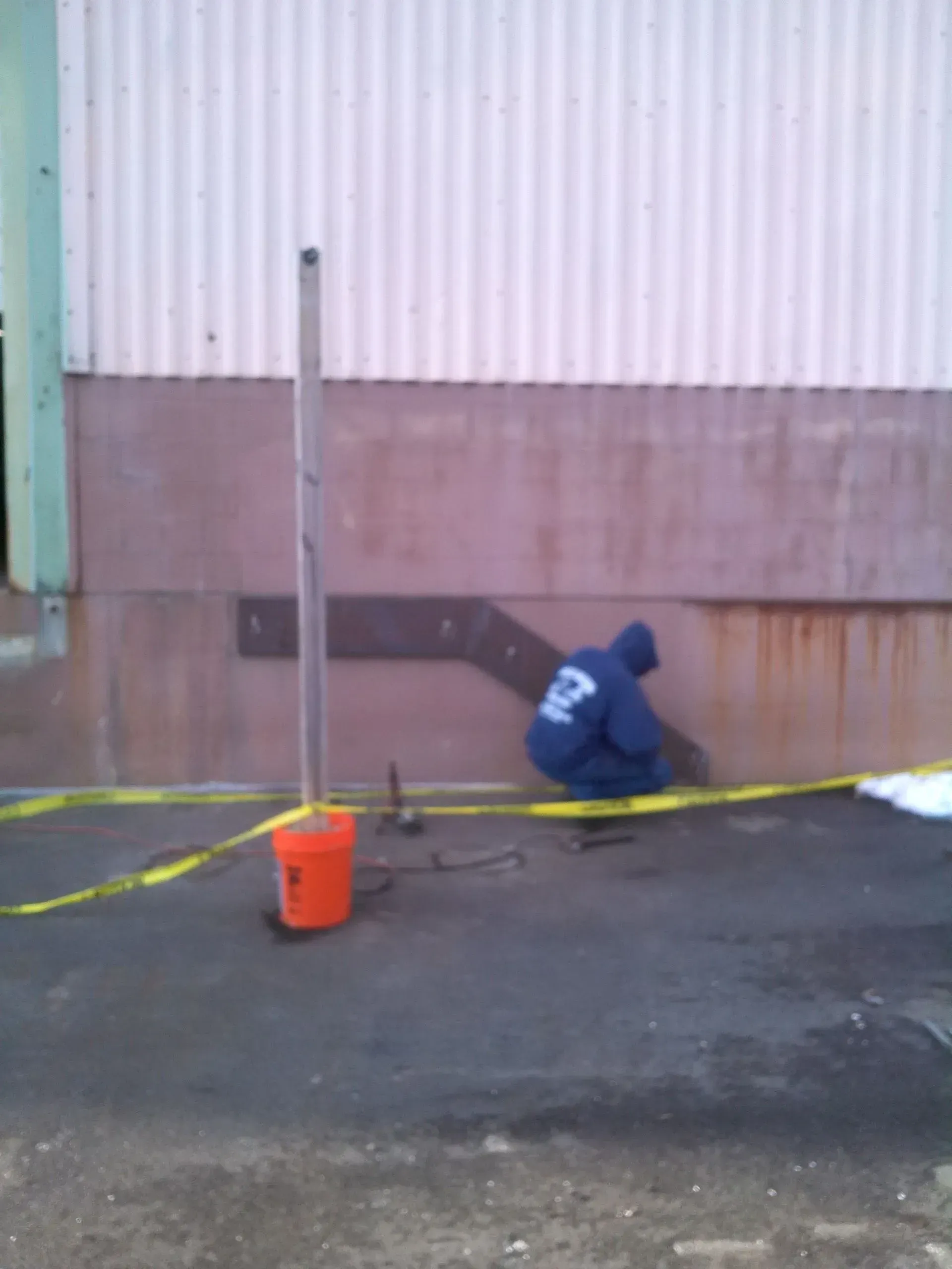 A man in a blue hoodie with the number 67 on the back is working on a wall.