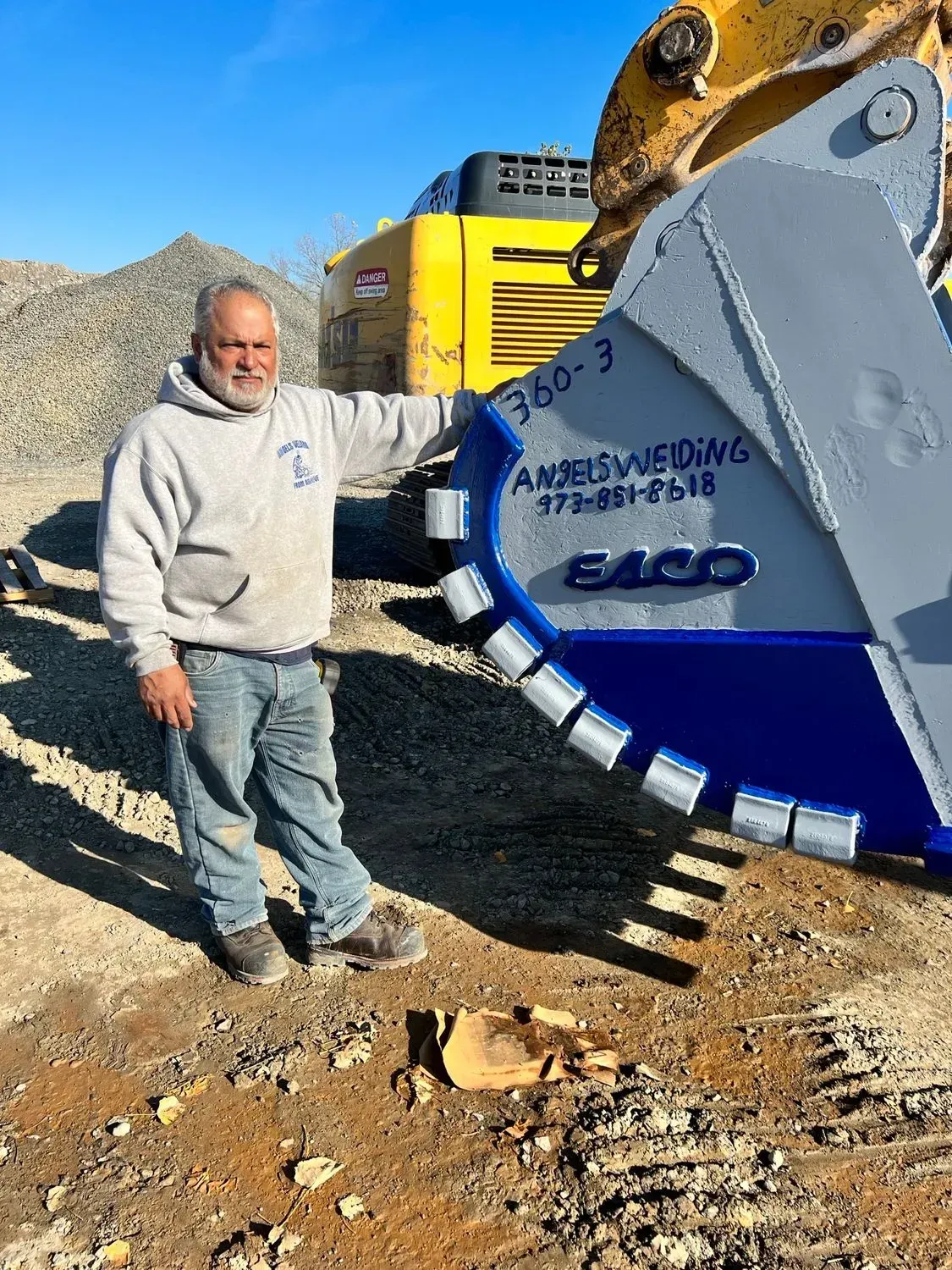 A man is standing next to a large bucket on a construction site.