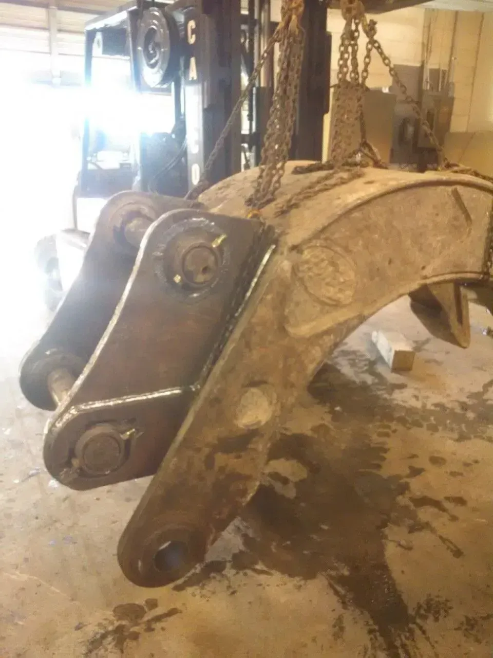 A large piece of metal is being lifted by chains.