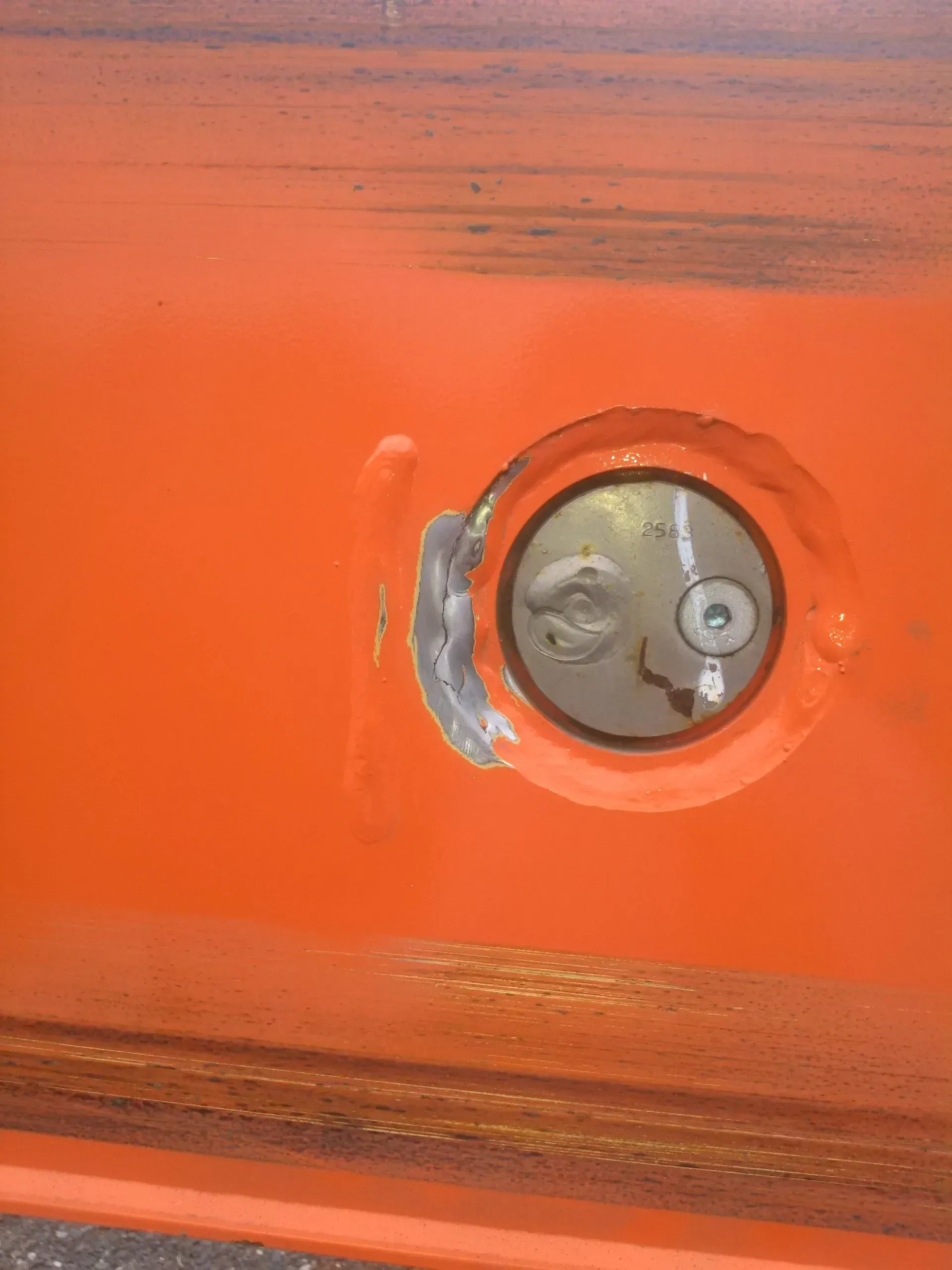 A close up of an orange door with a hole in it.