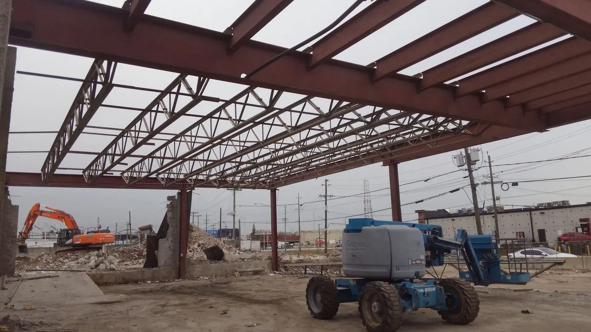 A blue tractor is parked under a metal structure.