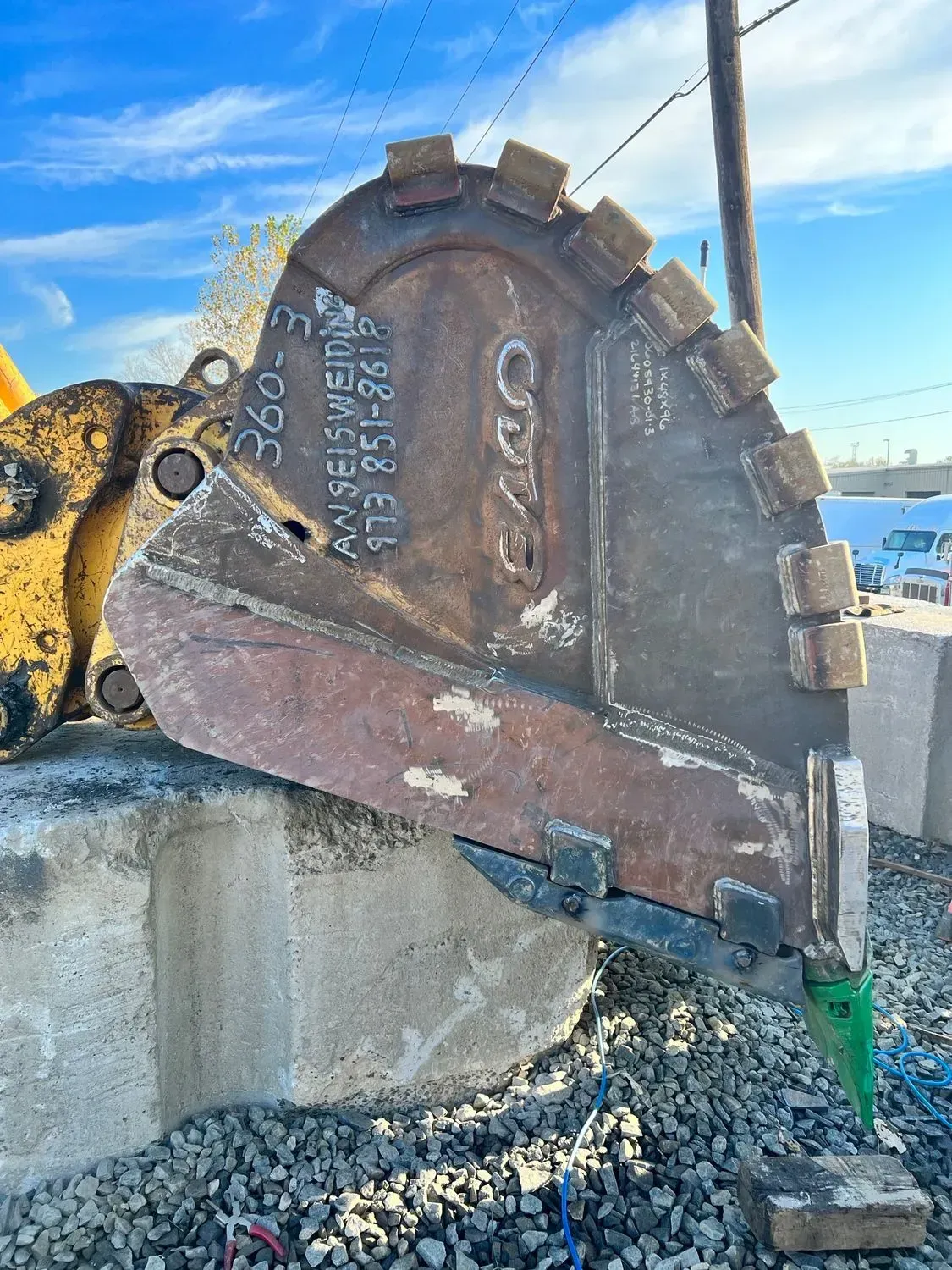 A large metal bucket is sitting on top of a pile of gravel.