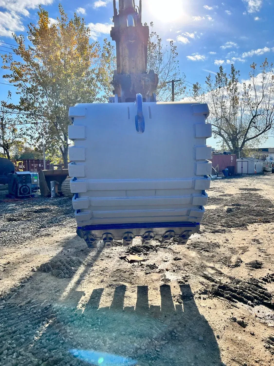 A large white box is sitting on top of a dirt field.