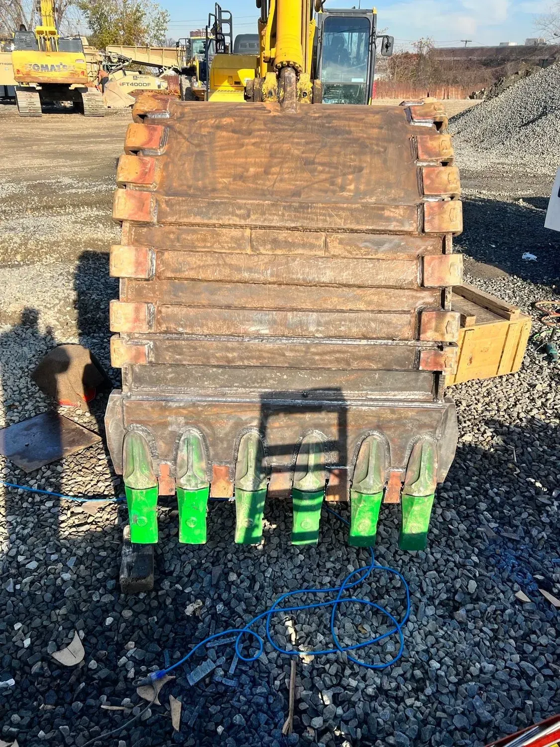 A large excavator bucket is sitting on top of a pile of gravel.
