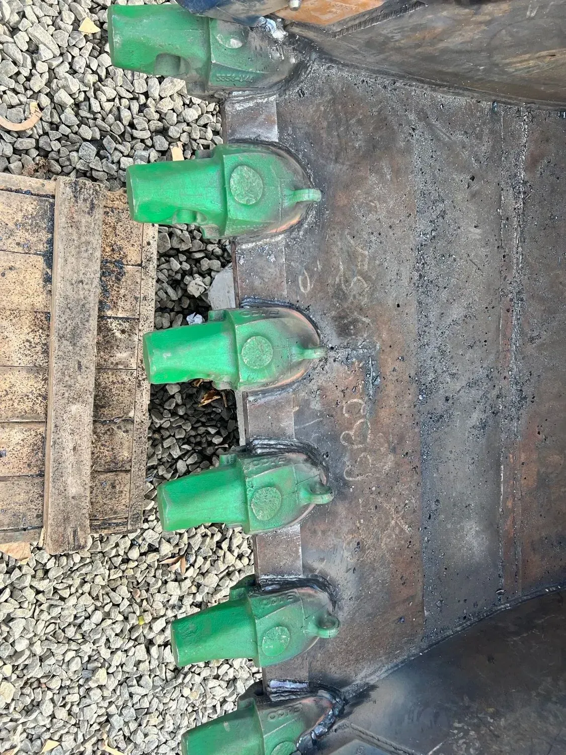 A close up of a bucket with green teeth on it.