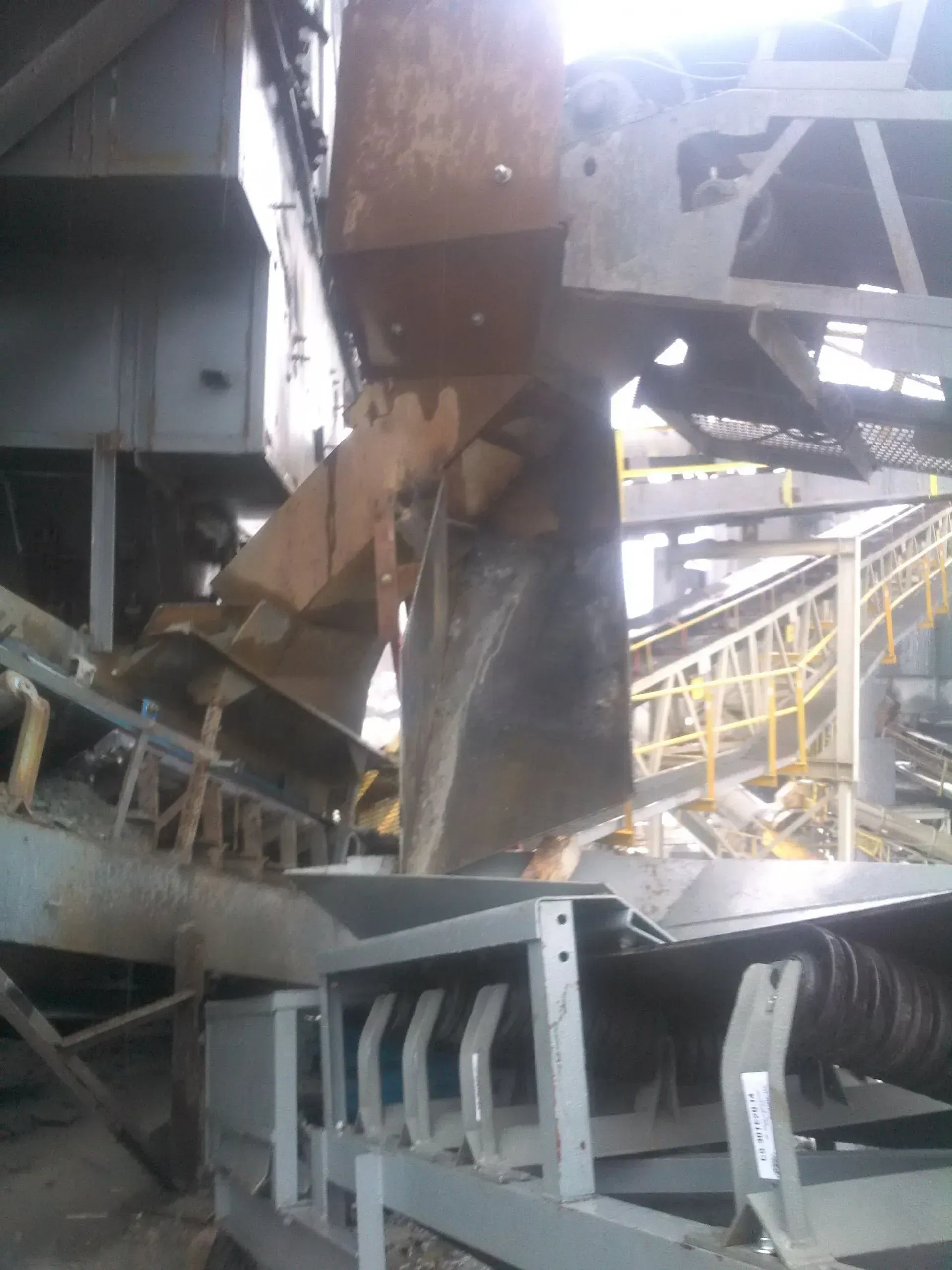 A conveyor belt is being loaded with a large bucket.