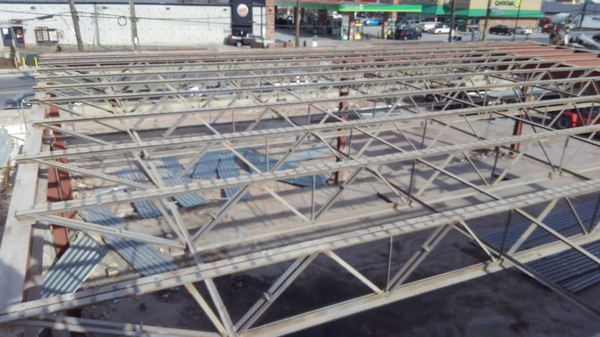An aerial view of a building under construction with a gas station in the background.