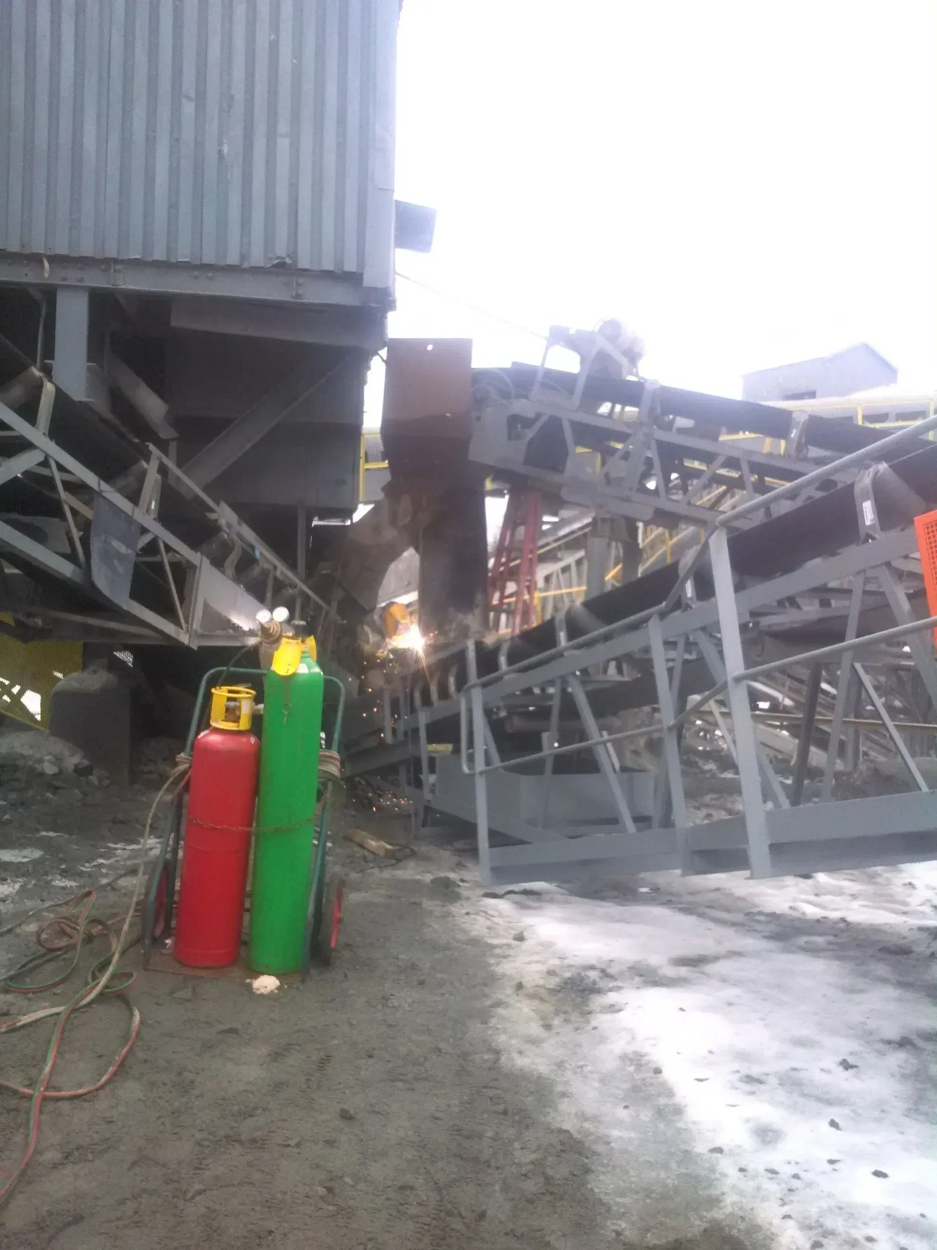 A couple of gas cylinders are sitting next to a conveyor belt.