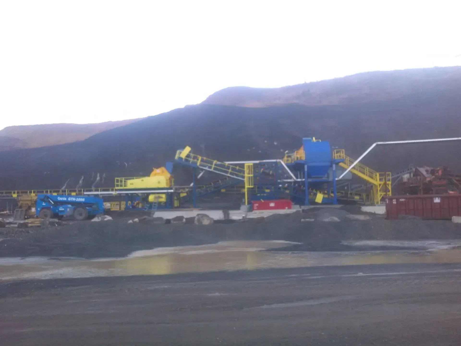 A large construction site with a lot of machinery and a mountain in the background.