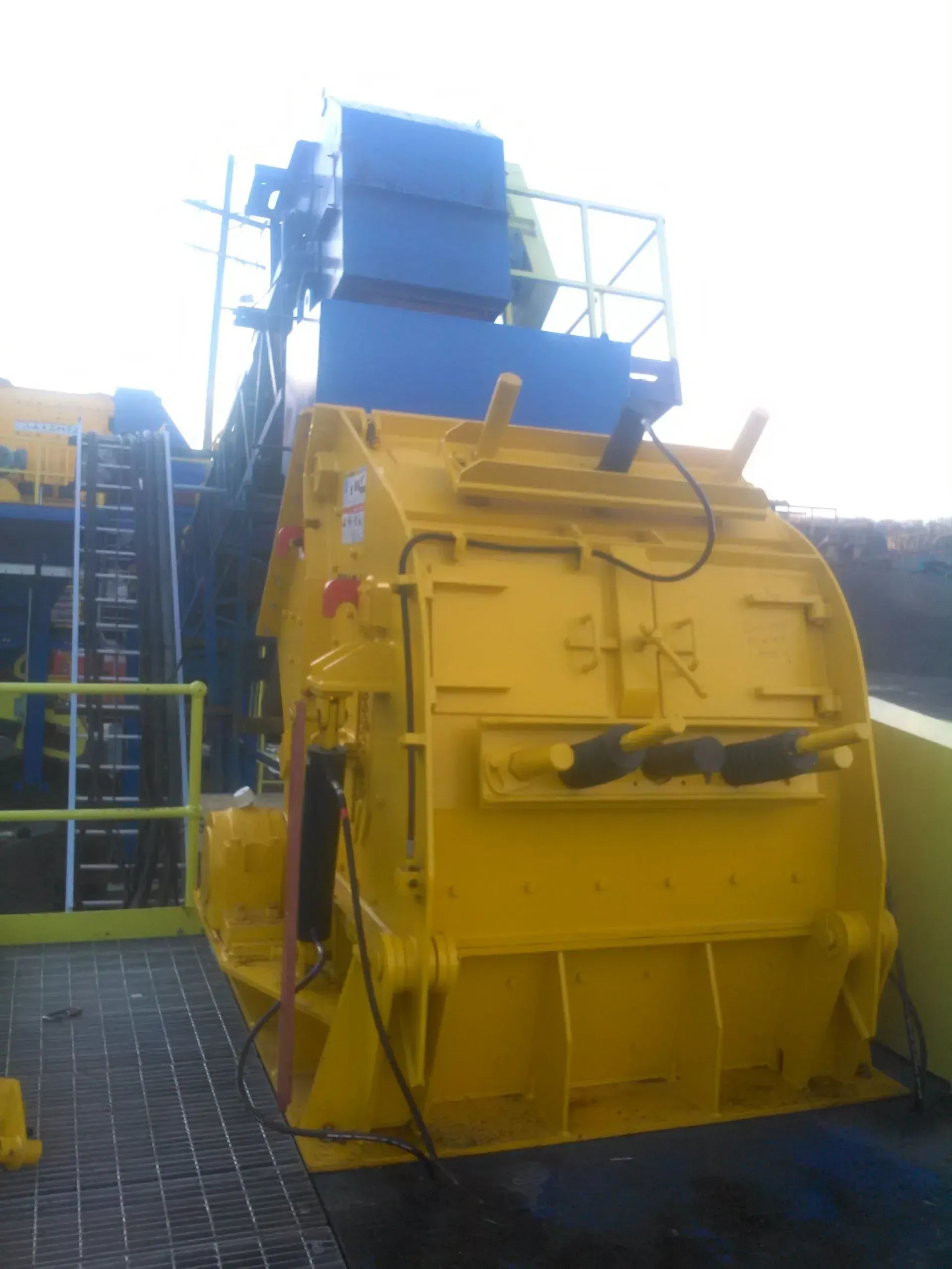 A large yellow machine is sitting on a brick floor.