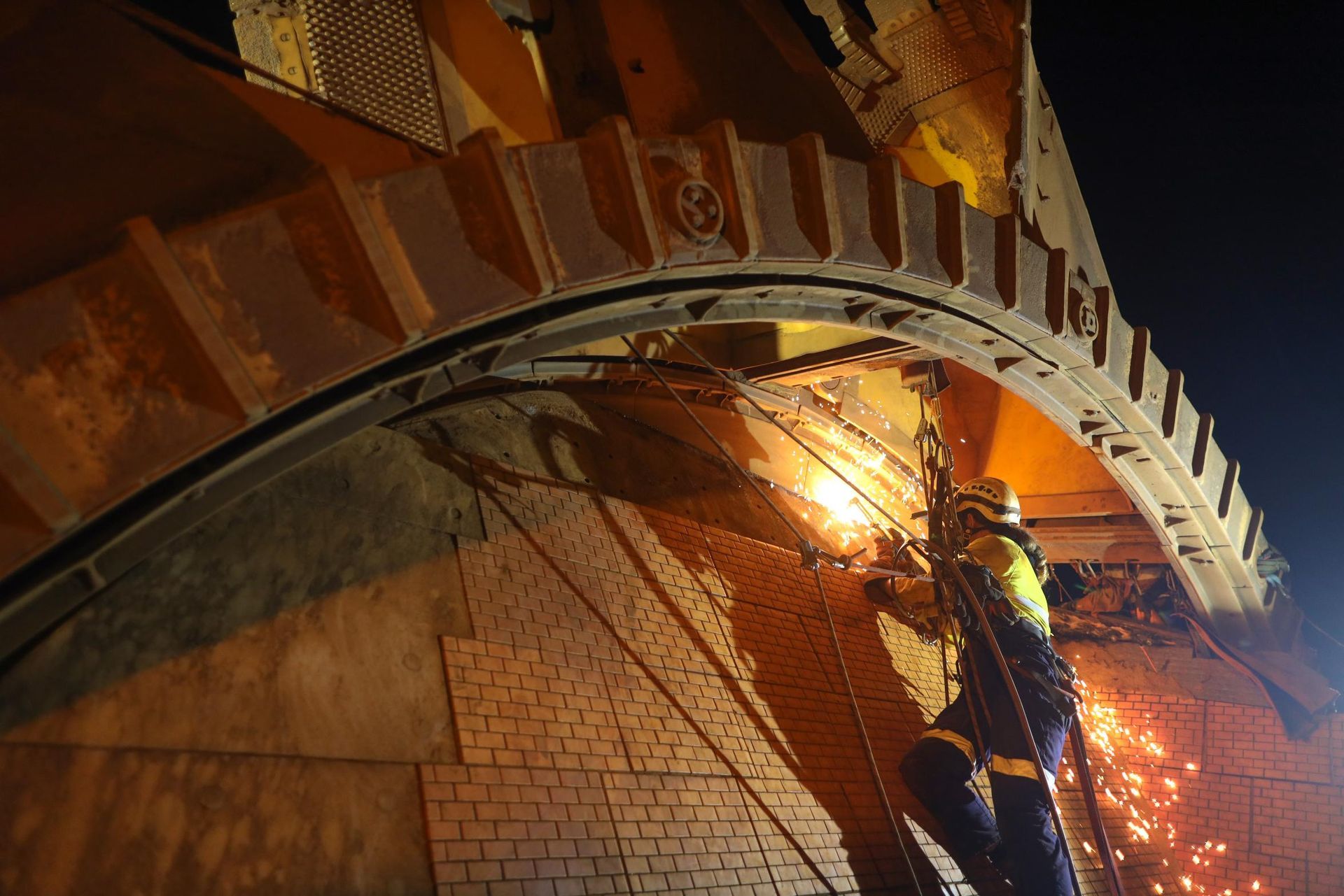 A man is working on a bridge at night.