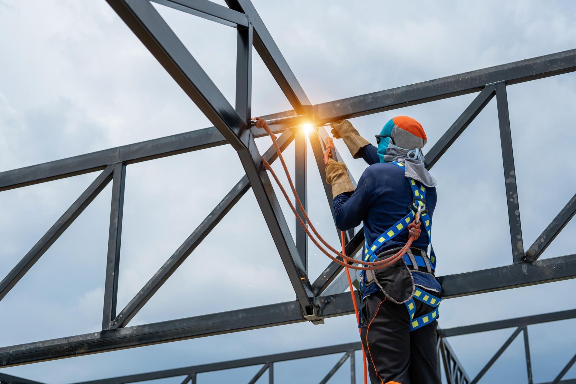 A man is welding a metal structure on top of a building.