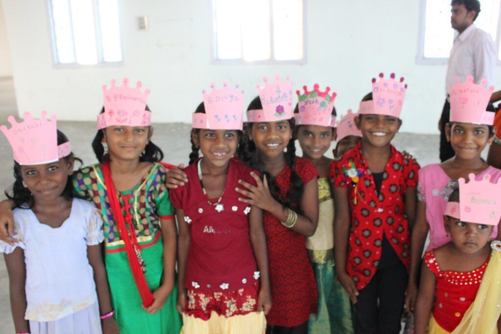 A group of young girls wearing pink crowns are posing for a picture.