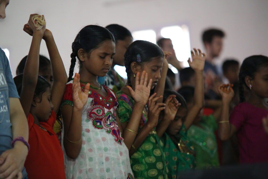 A group of children are raising their hands in the air
