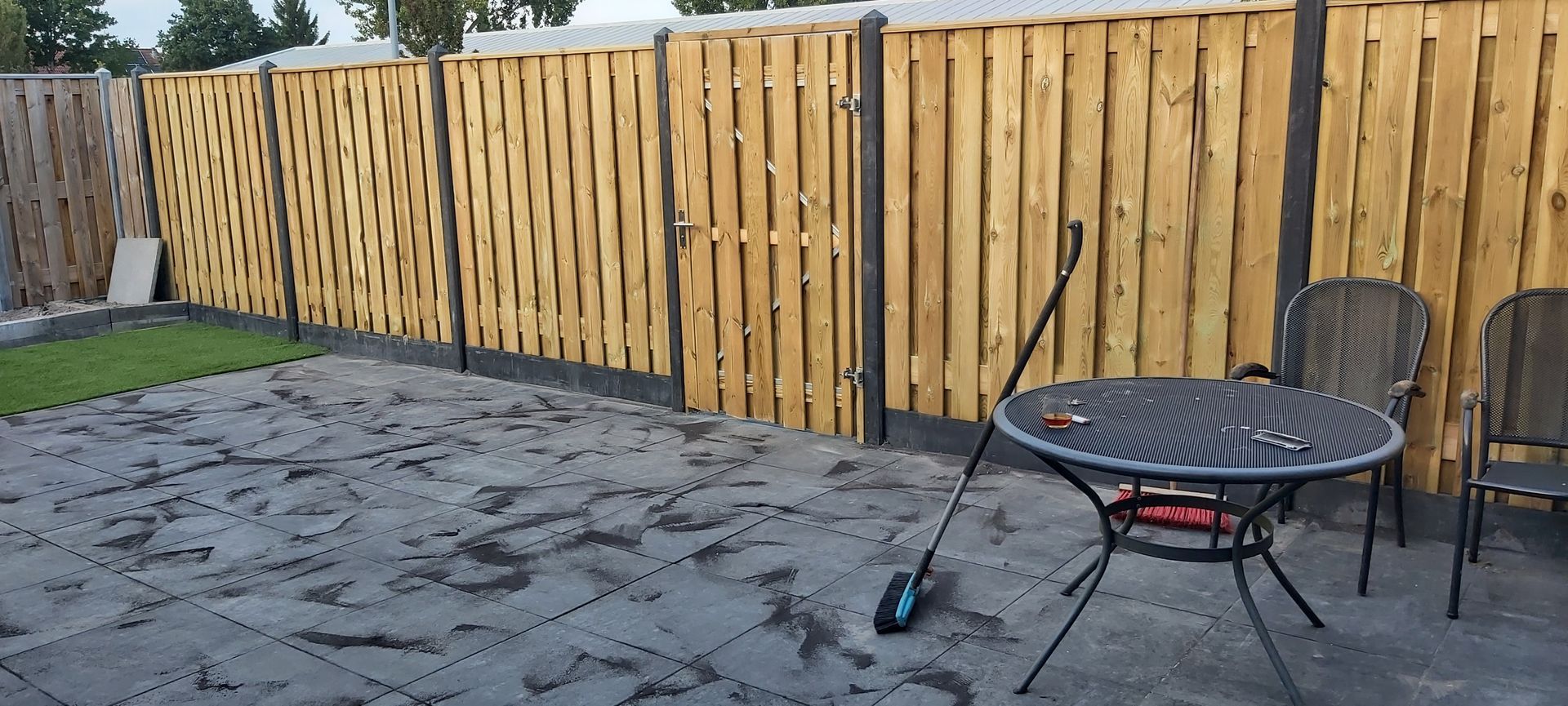 Een houten hek omringt een patio met een tafel en stoelen.