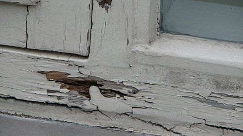 Een close-up van een raam met afbladderende verf erop