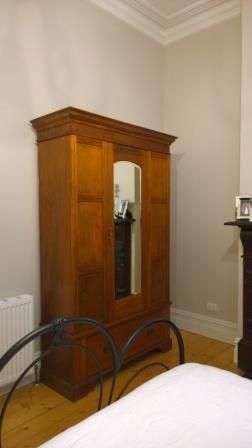 A bedroom with a wooden wardrobe and a bed.