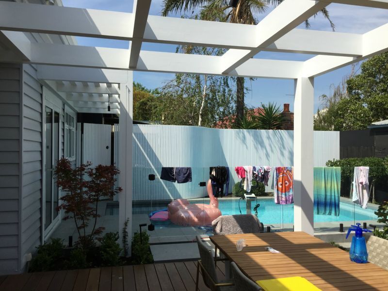 A pink flamingo is floating in a pool next to a table and chairs