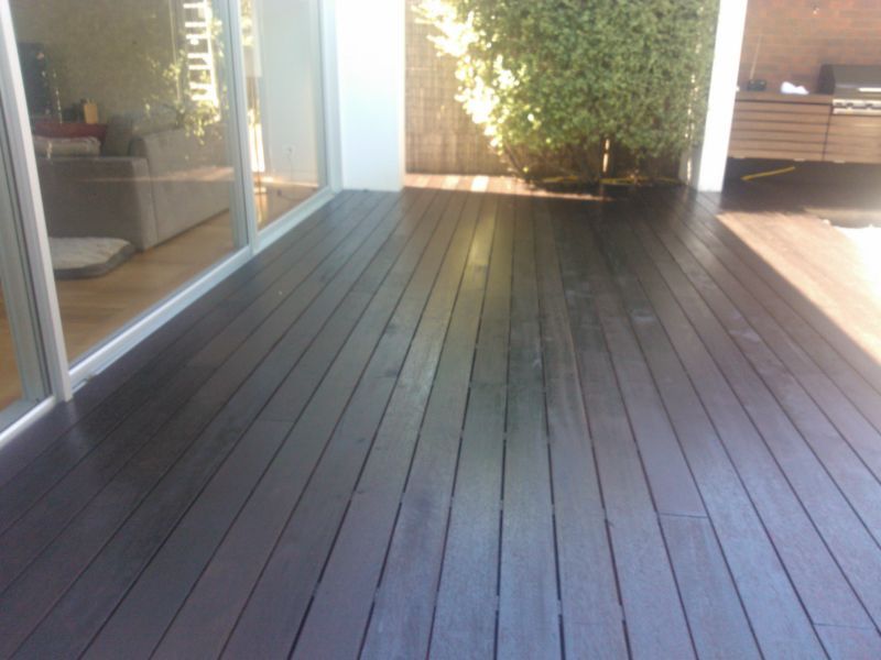 A dark wooden deck with a sliding glass door