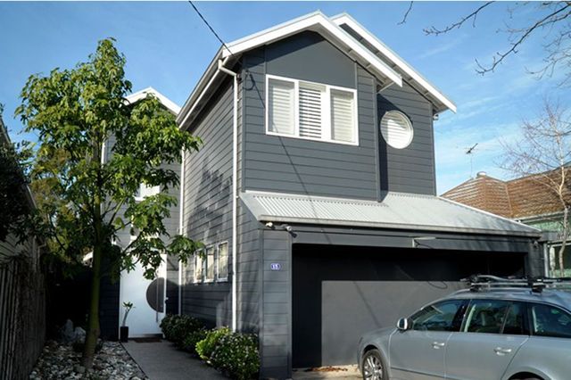 Two-story modern home with dark grey siding, a garage, and a car parked in front. A small tree is visible on the left.