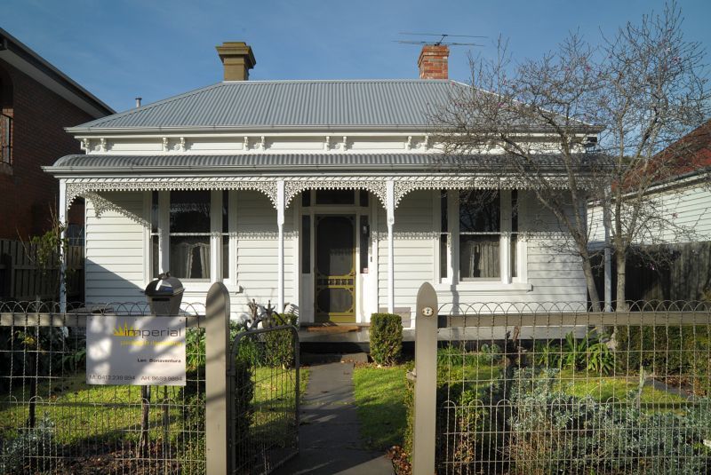 A white house with a metal roof is for sale
