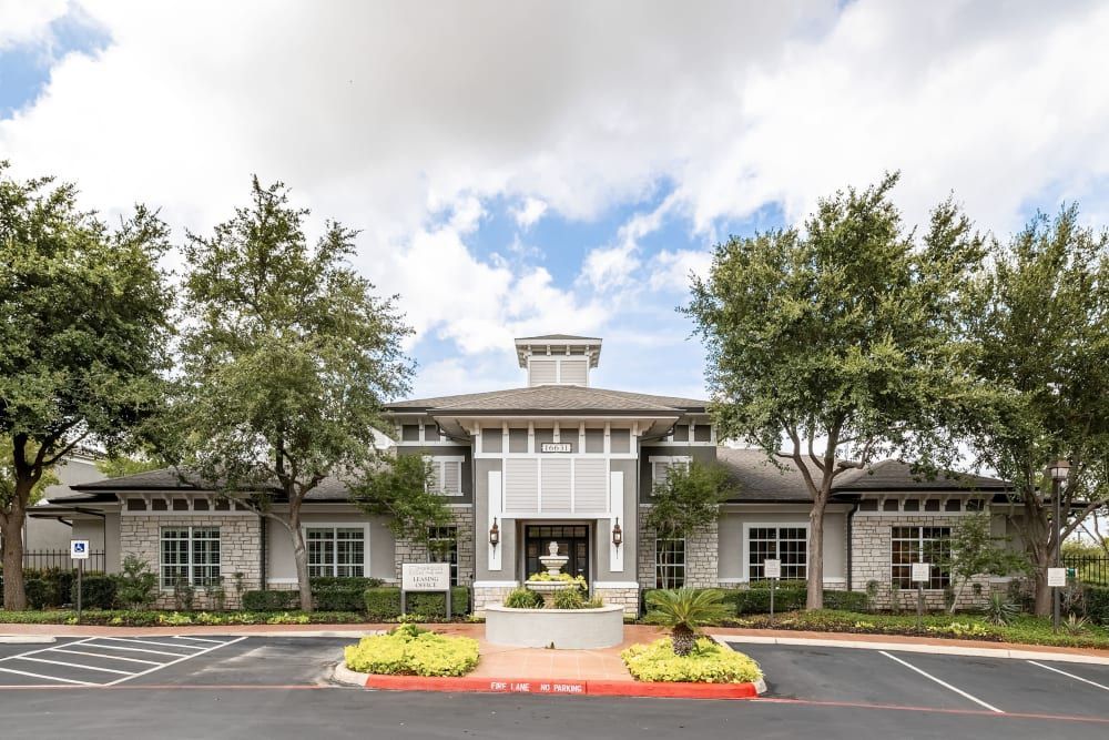 Apartment leasing office exterior view with a lot of windows and trees at Marquis at The RIM in Northwest San Antonio, TX.