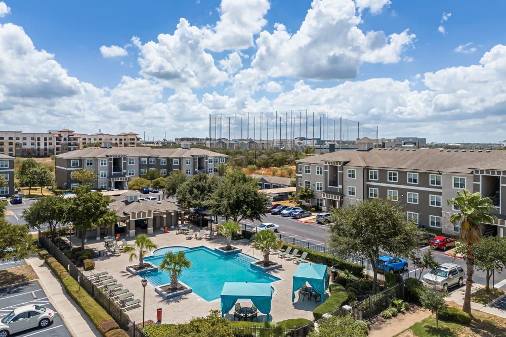 An aerial view of a large swimming pool surrounded by buildings at Marquis at The RIM in Northwest San Antonio, TX.