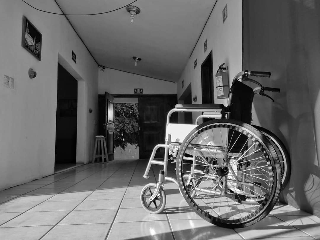 Una fotografía en blanco y negro de una silla de ruedas en un pasillo.