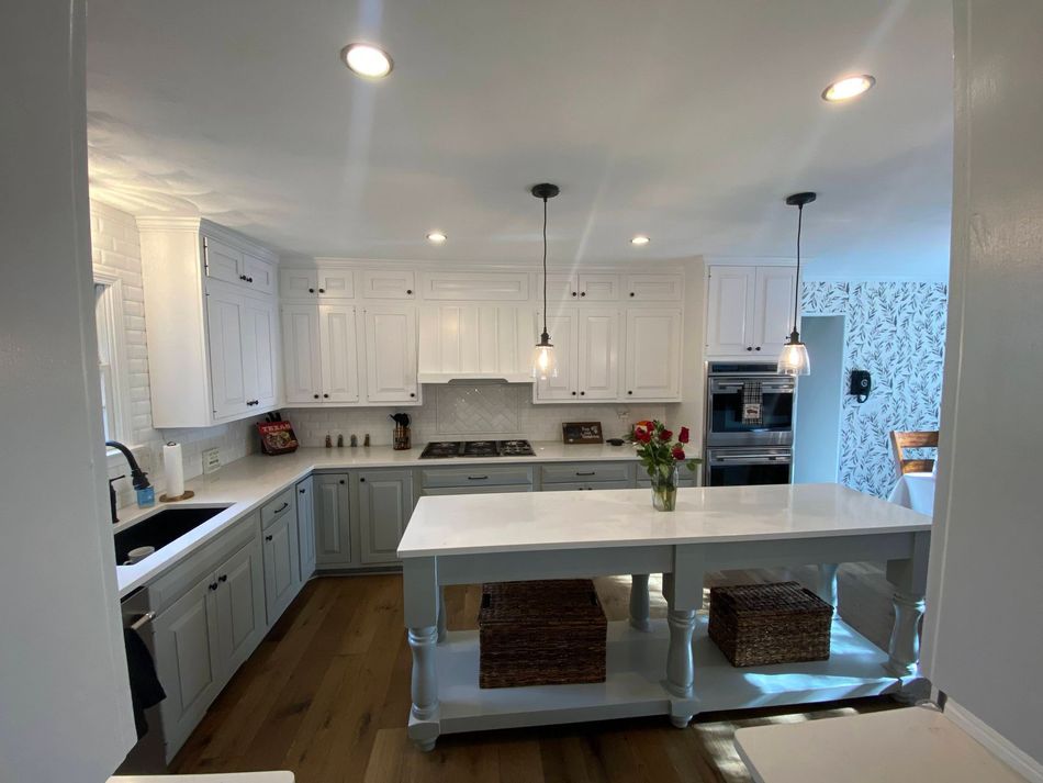 Bright white kitchen with large island, pendant lights, and built-in ovens