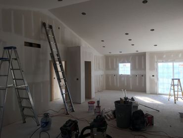 Partially renovated room with ladders, tools, and drywall under construction