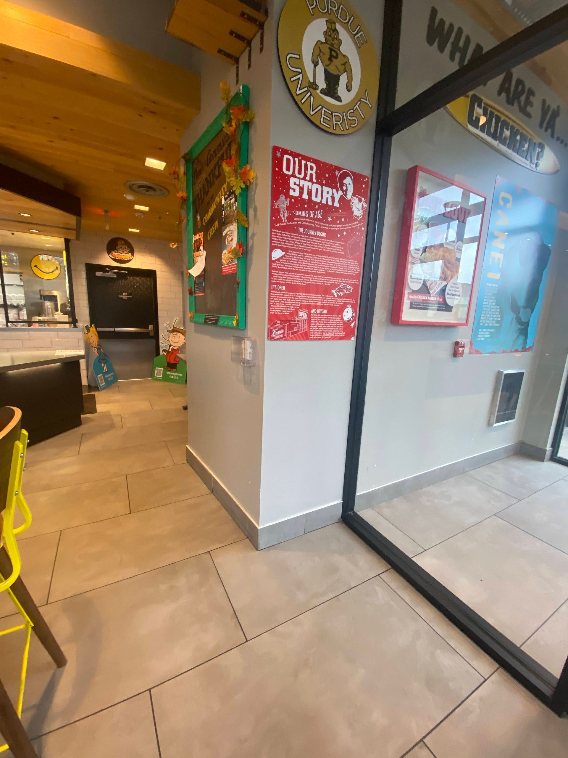 Cafe interior with tiled floor, wall posters, and a large mirror reflecting the seating area.