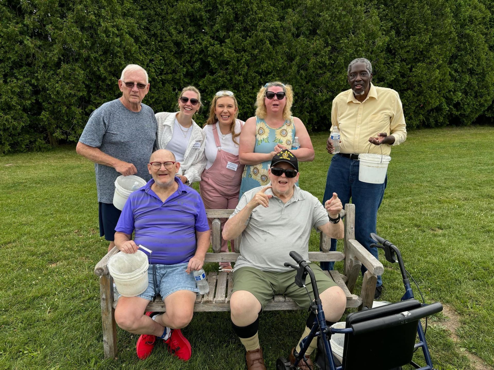 A group of people are sitting on a bench in a park.