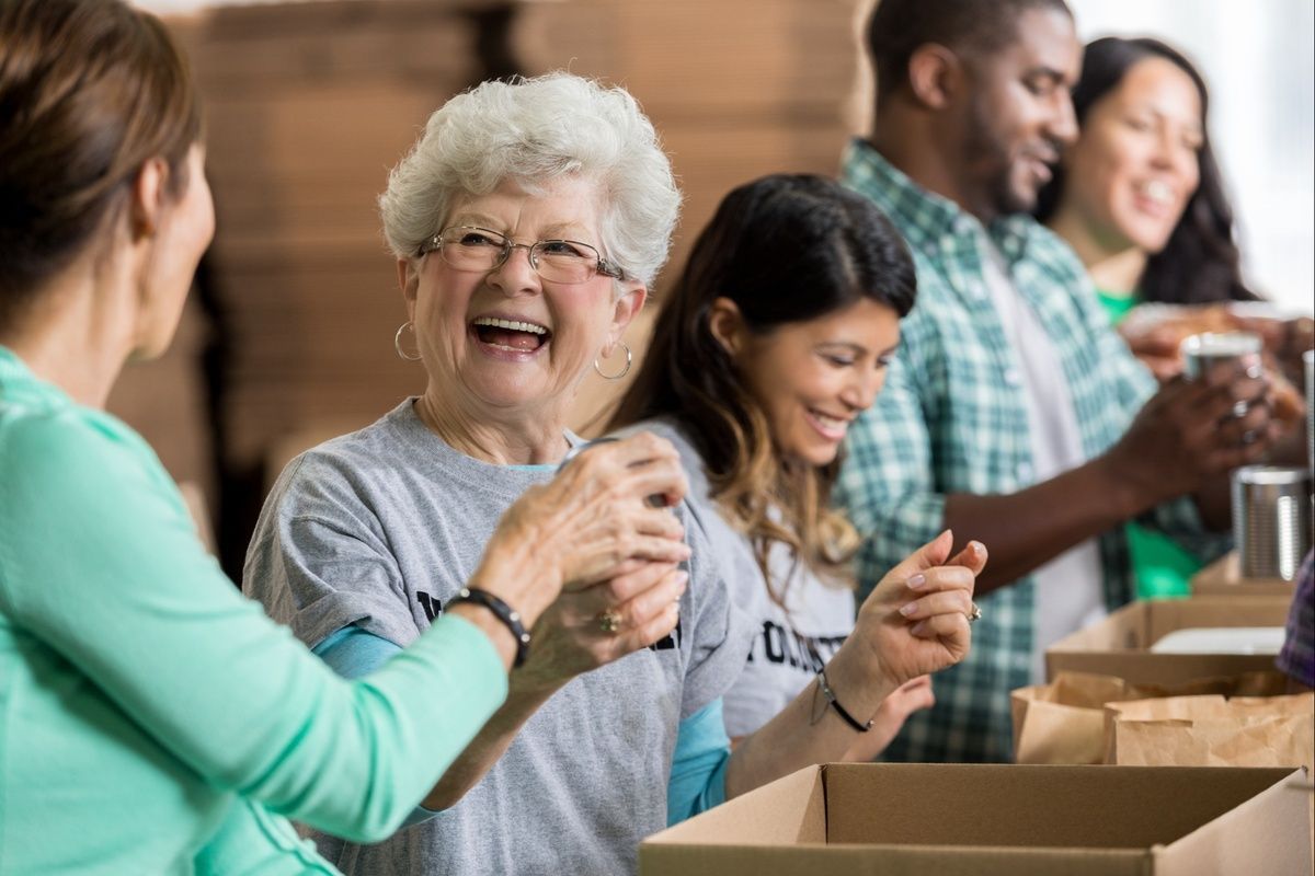 A group of people are sitting around a table with boxes and laughing.