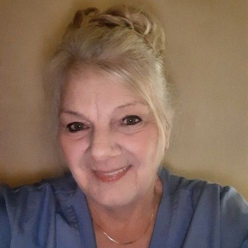 A woman in a blue shirt is smiling for the camera.