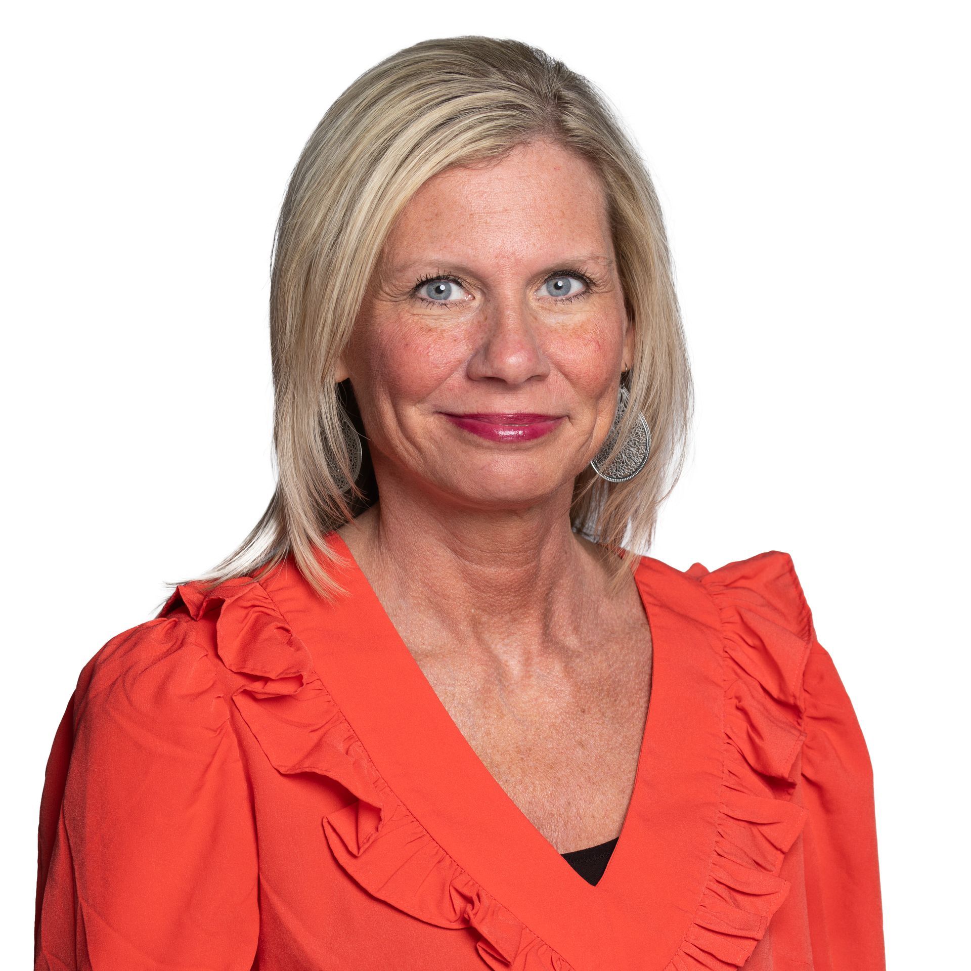 A woman wearing a red ruffled top is smiling for the camera