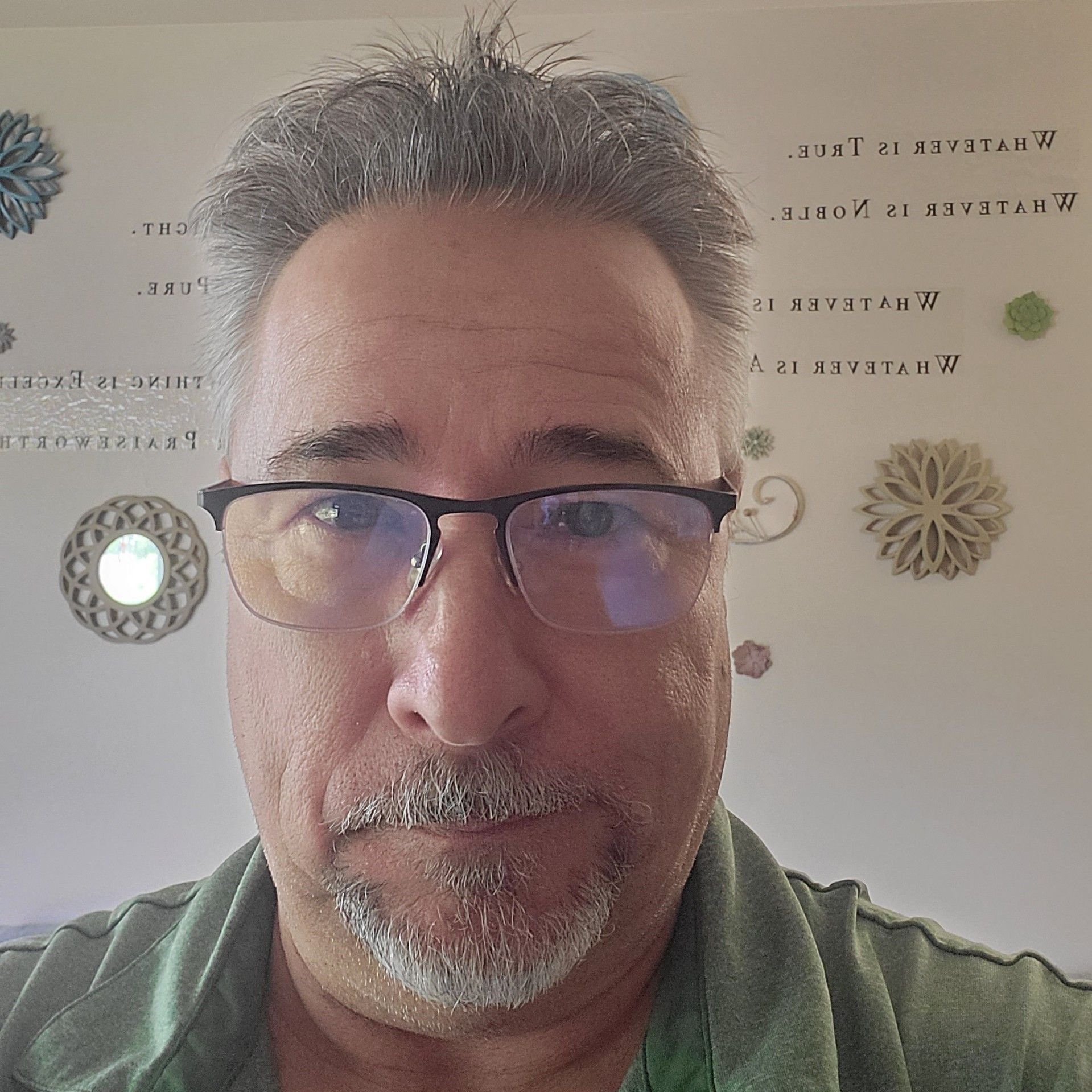 A man with glasses and a beard is wearing a green shirt