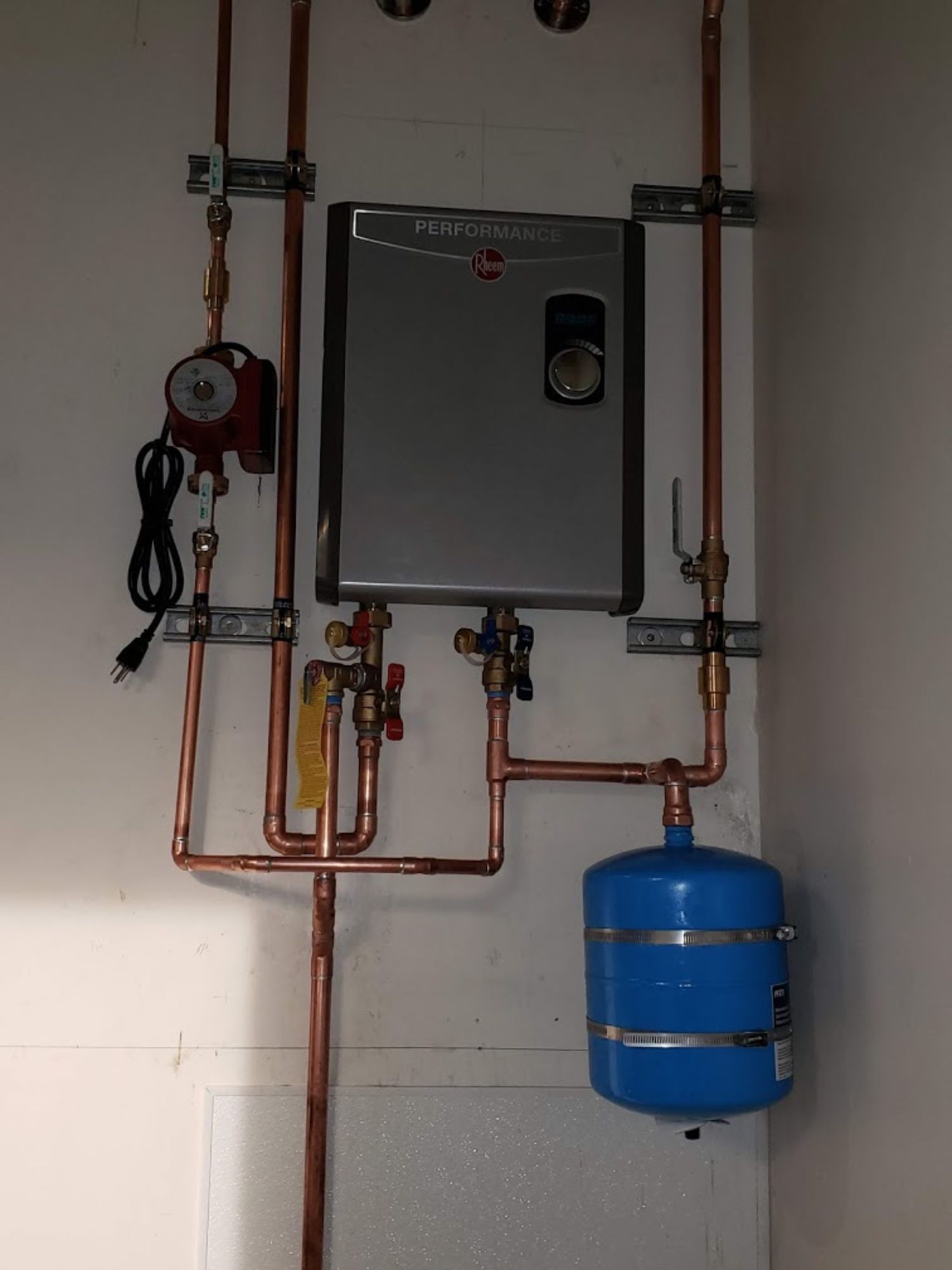 A water heater is attached to a wall with copper pipes