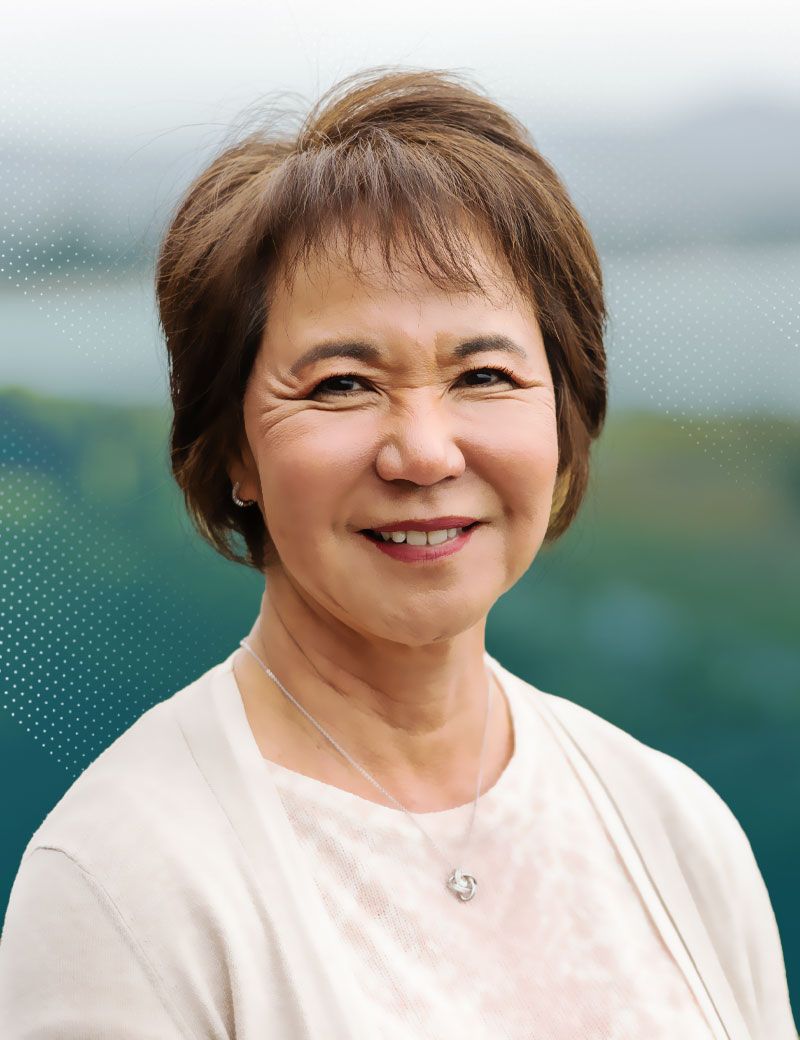 Natolie smiling woman with short brown hair wearing a beige cardigan, outdoors.