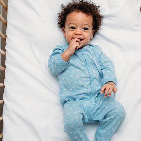 Happy Baby Boy Lying in a Crib Wearing Pajamas — Jackson, MS — Capital City Children & Adolescent Clinic, PLLC