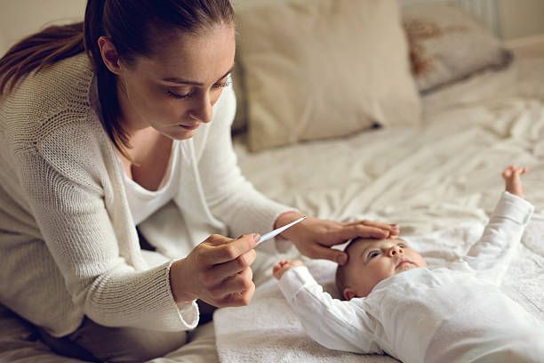 Worried Mother Measuring Baby's Temperature in Bedroom — Capital City Children & Adolescent Clinic, PLLC