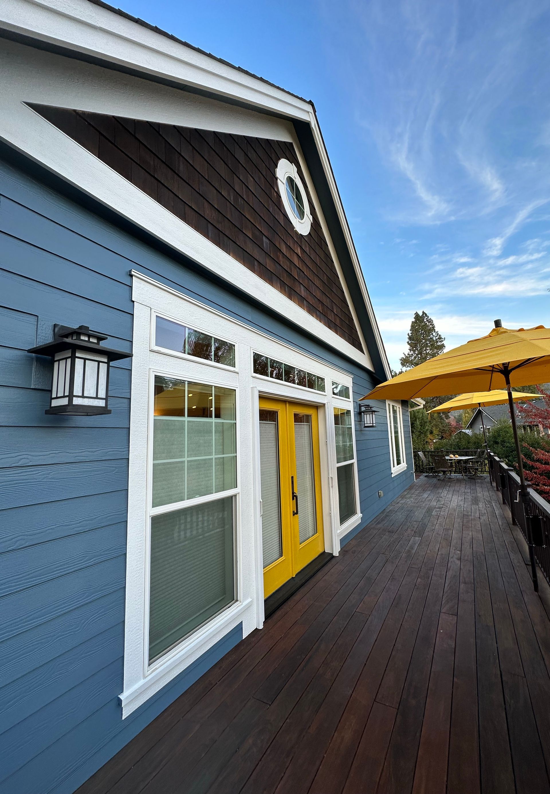 A blue house with a wooden deck and yellow umbrellas