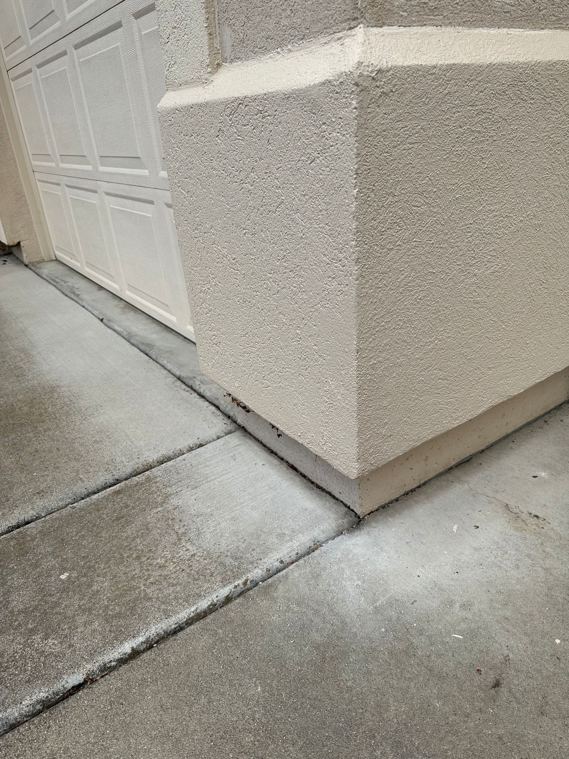 A close up of a sidewalk next to a garage door.